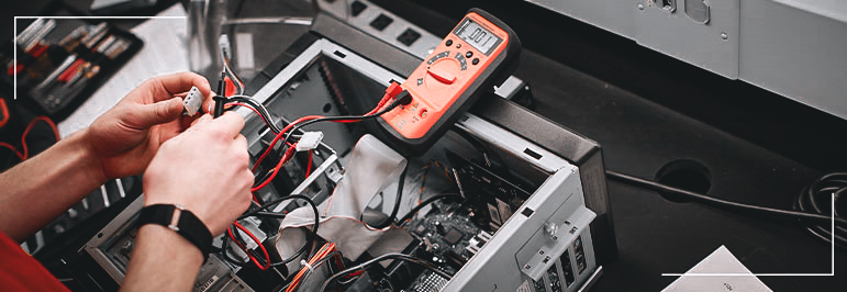 Person checking the power supply of a computer using a multimeter